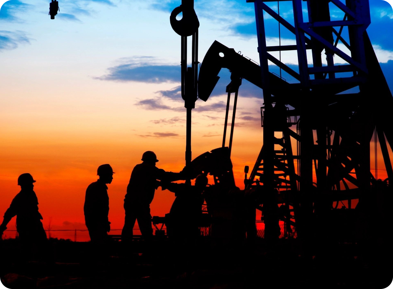 Two men are standing in front of a pump jack.