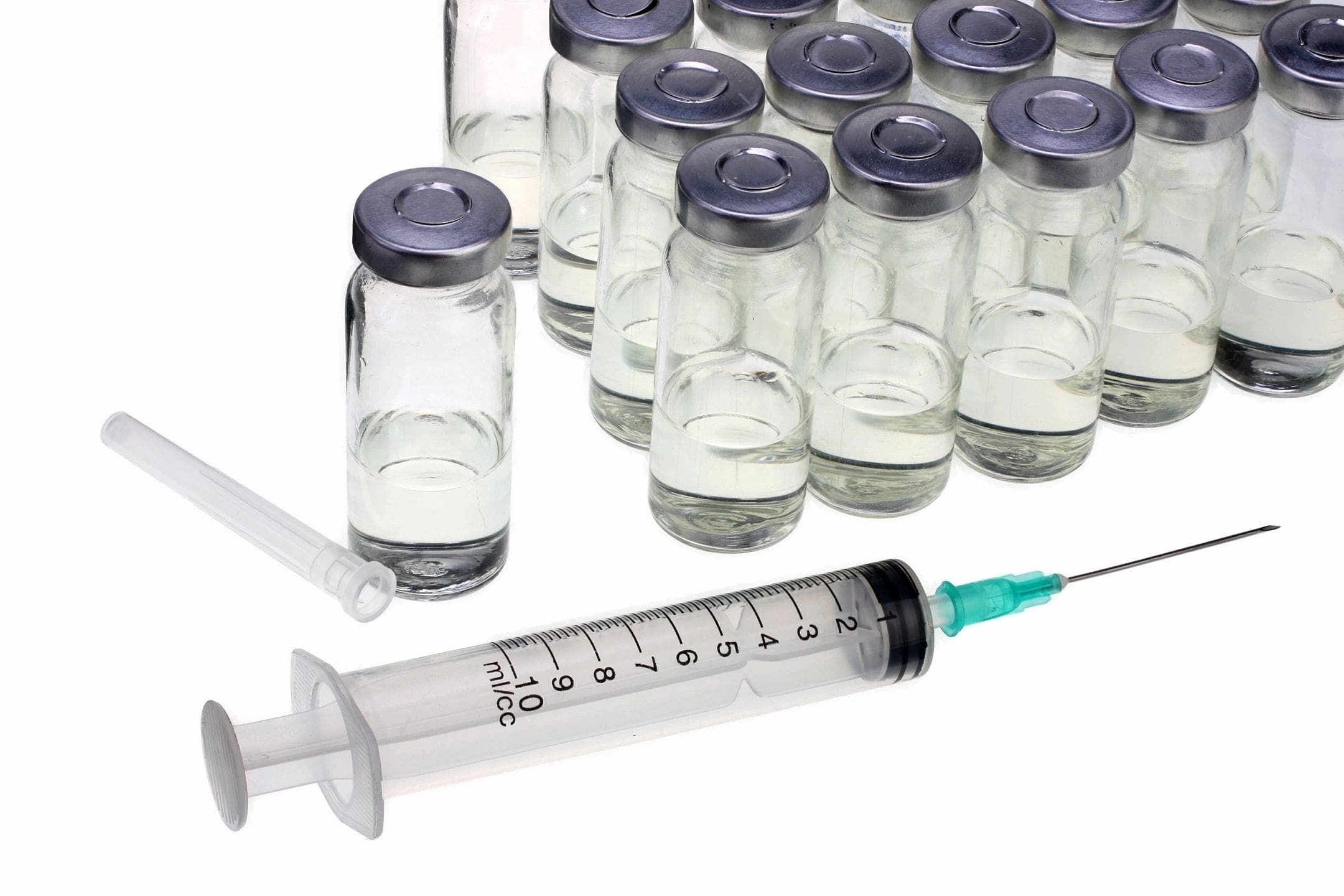 A group of empty glass vials next to an injection needle.