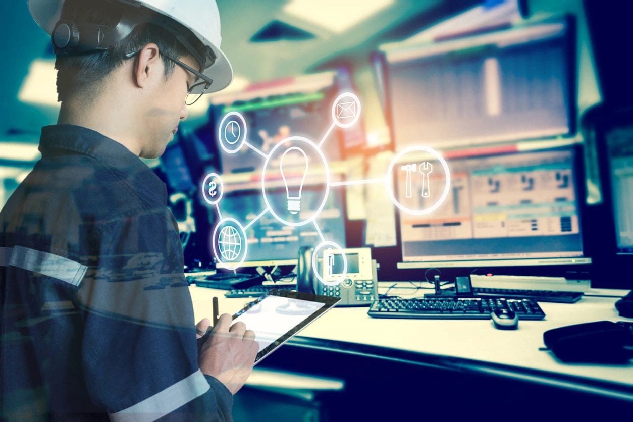 A man in hard hat using tablet computer at work.